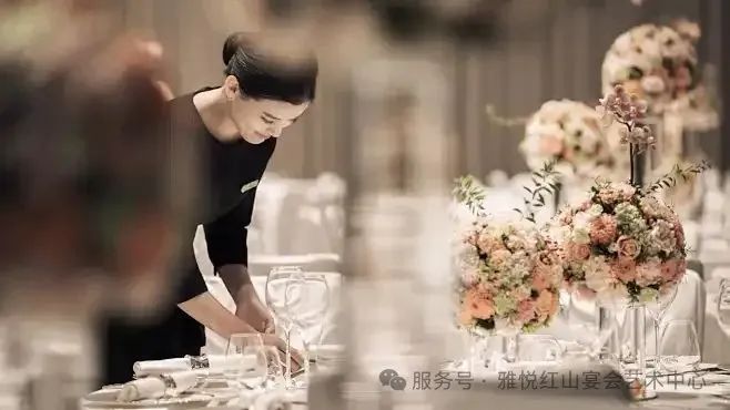 酒店服务员用粉红玫瑰、插花布置正式宴会桌